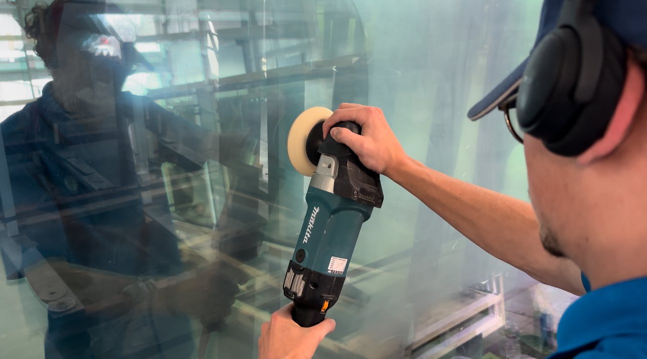 Technician polishing a scratch out of a large glass panel